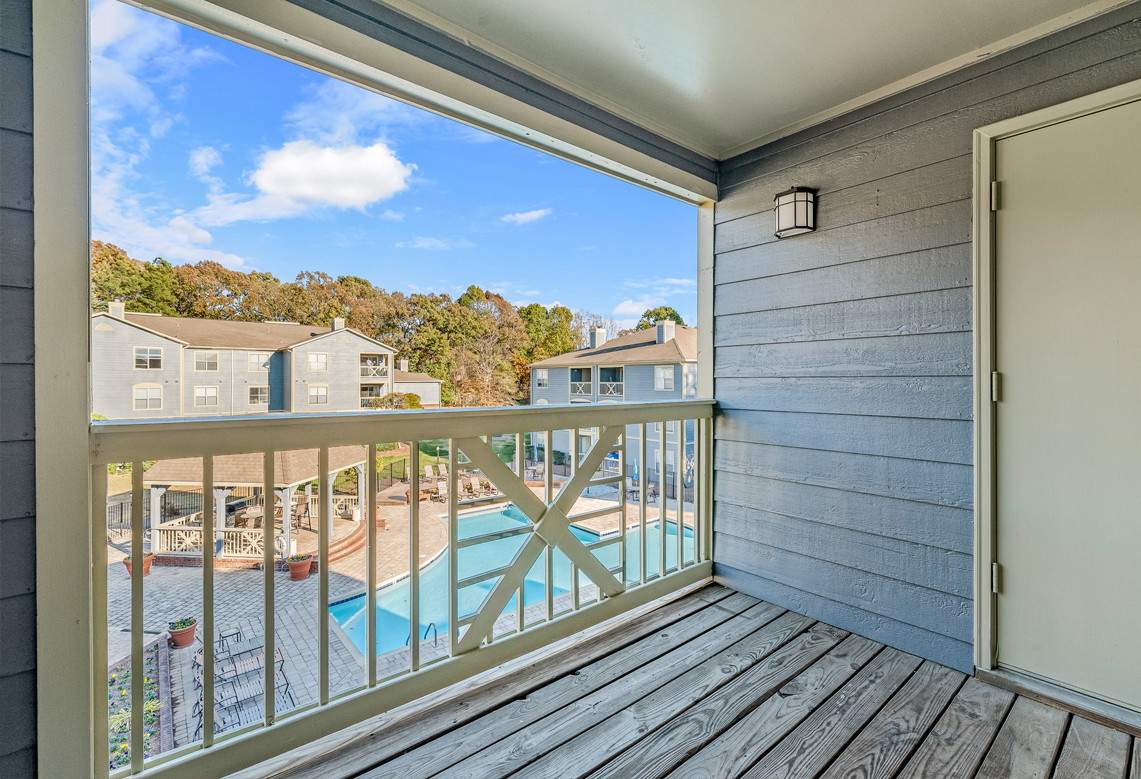 an outdoor wooden deck with a railing near some buildings